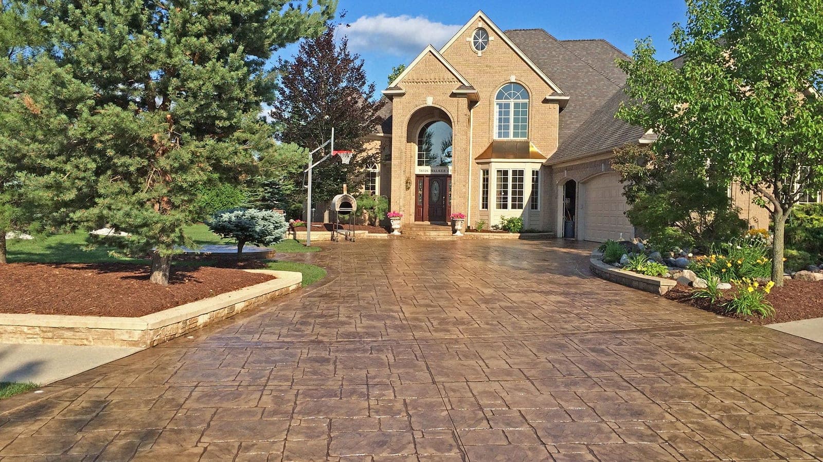 Stamped concrete driveway sealed in a gloss finish in front of a brick estate home in London, Ontario by TriCity Concrete Sealing